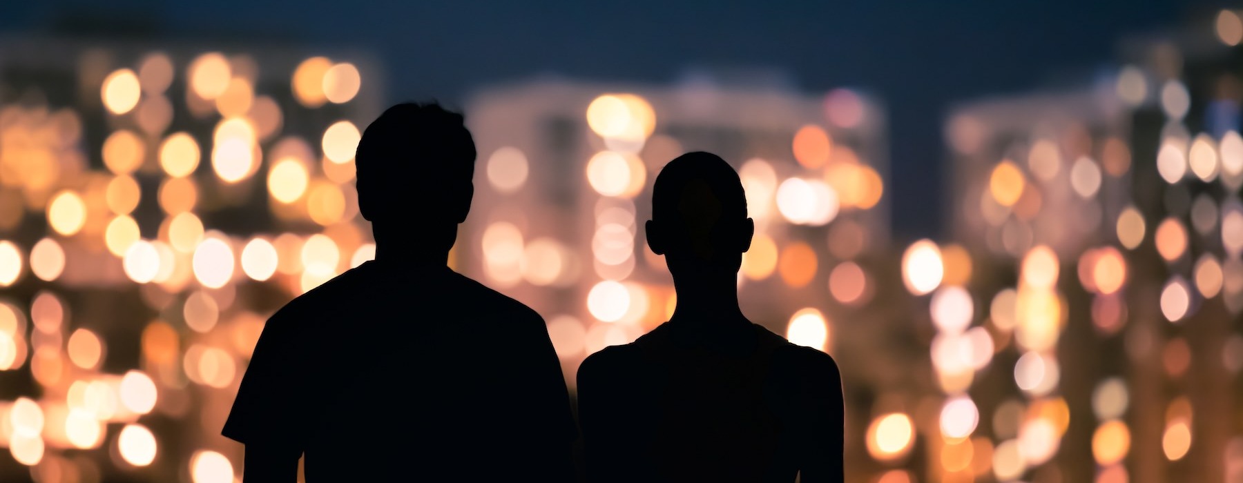a man and a woman looking at a city at night