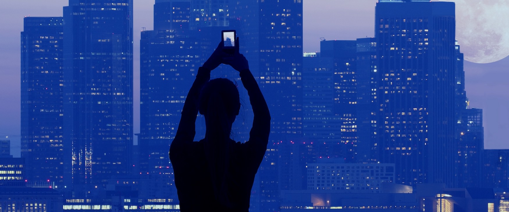 Close to the center of everything a person taking a picture of a skyline
